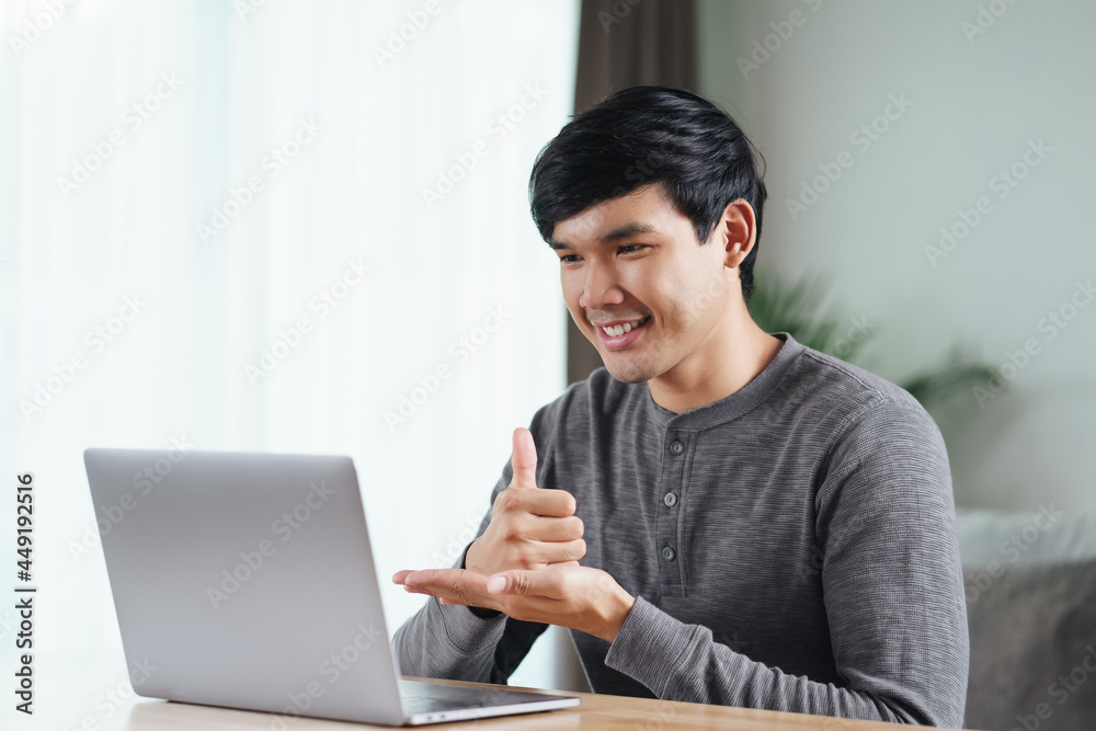 Young Asian man deaf disabled using laptop computer for online video conference call learning and communicating in sign language.. Young Asian man deaf disabled using laptop computer for online video conference call learning and communicating in sign language..