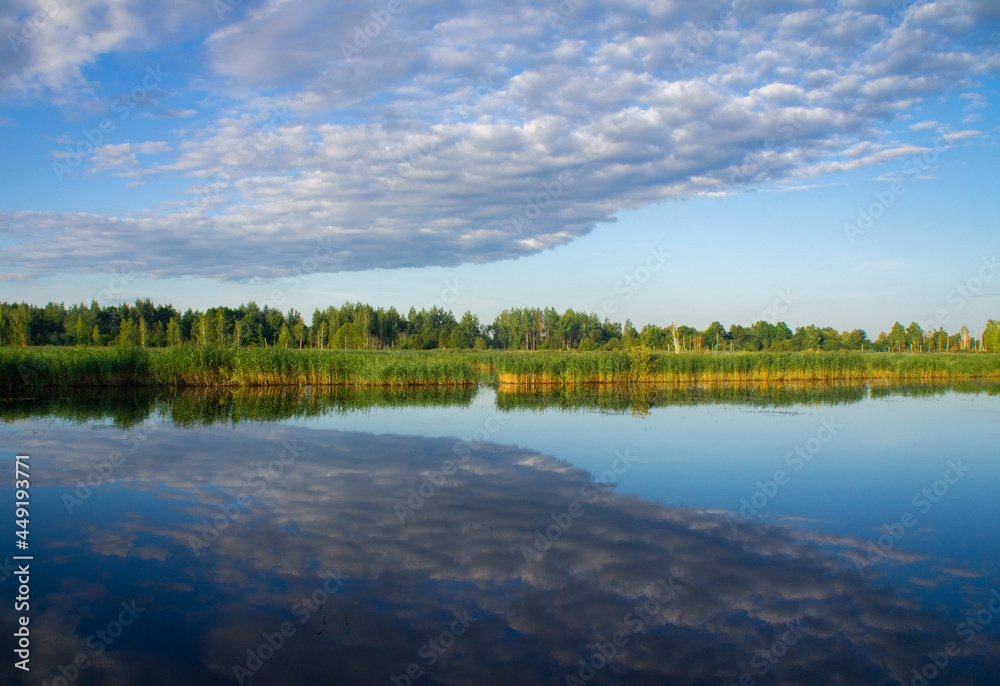 Obraz premium Beautiful calm blue landscape at the sunset of the lake. Reflection of clouds in the water