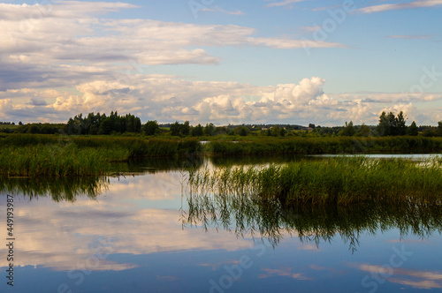 Beautiful calm blue landscape at the sunset of the lake. Reflection of clouds in the water © Payllik