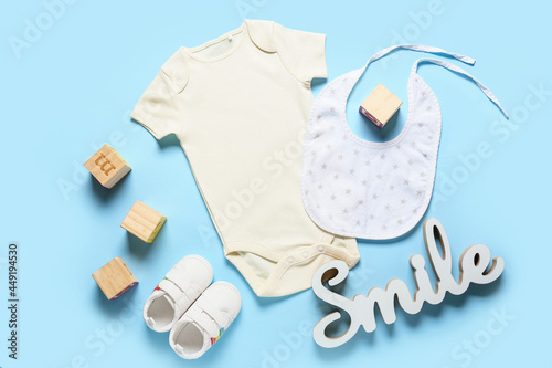 Composition with baby clothes, shoes and bib on color background