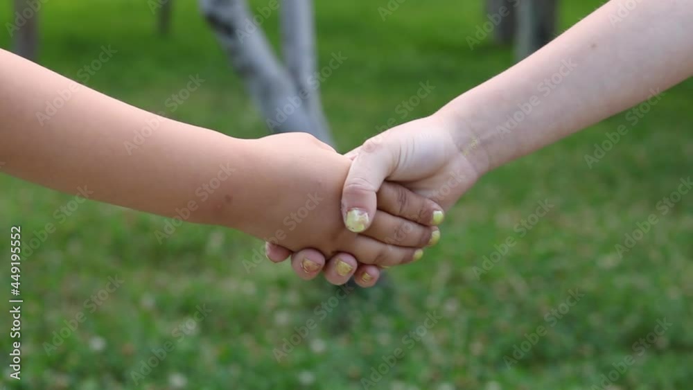 Kids shake hands in the park, blurred backround Kids shake hands in the park, blurred backround