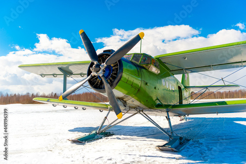 An old classic airplane. The biplane stands in the snow on skis in winter against the sky - preparing to fly. Retro airplane at the airport in nature. Winter air transportation of passengers and cargo