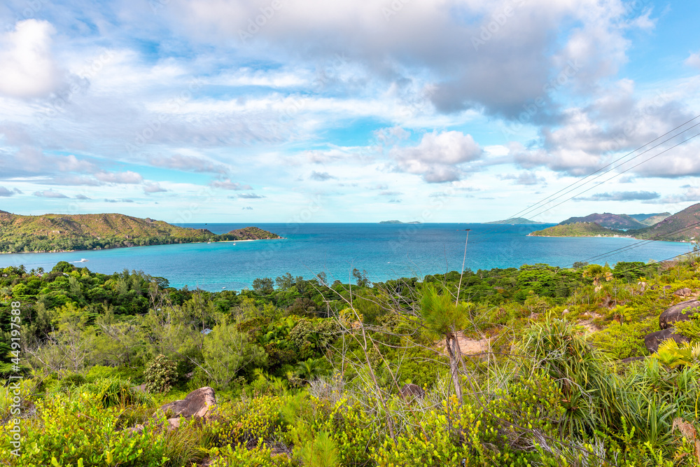Landscape view of Praslin Island, Seychelles, seen from Zimbabwe Point (Grand Fond), with lush tropical vegetation and turquoise water overlooking Praslin coastline with Curieuse Island.