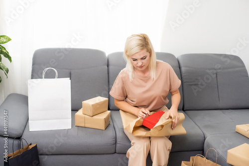 Smiling satisfied young woman customer sit on sofa unpack package open parcel, happy woman consumer holding cardboard box receive good online shop purchase at home, post mail shipping delivery concept photo