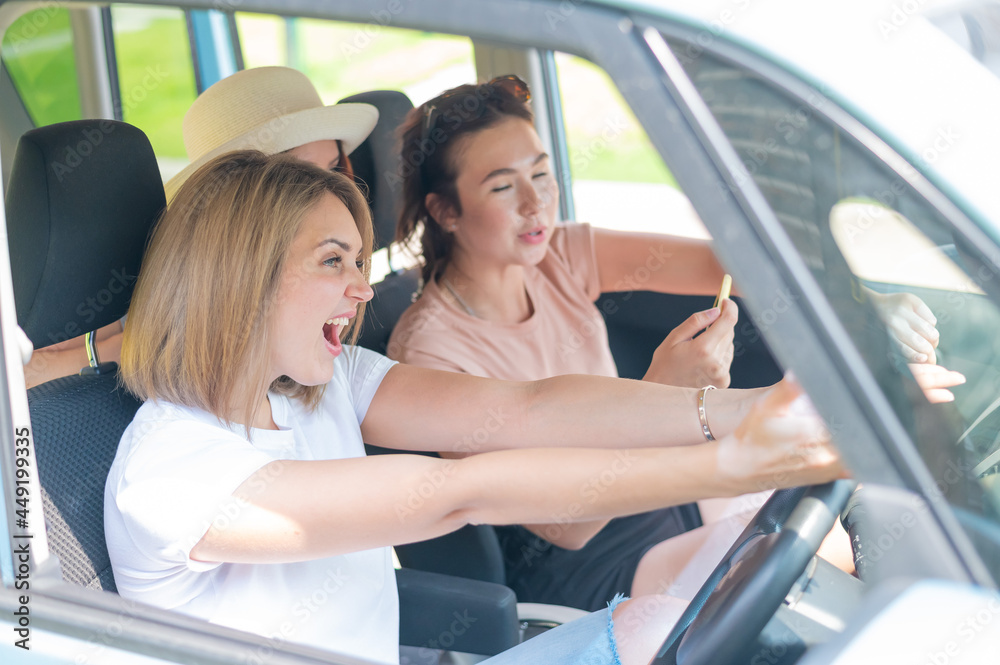 Three friends go on a trip. Caucasian women drive in a car and point fingers in surprise.