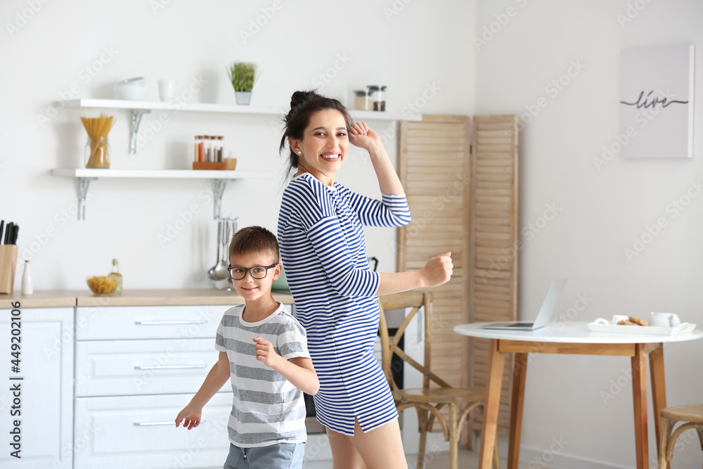 Young woman and her little son dancing in kitchen