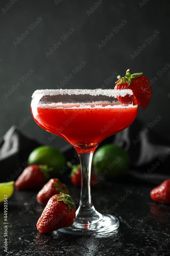 Glass of strawberry daiquiri cocktail, limes and berries on dark background Glass of strawberry daiquiri cocktail, limes and berries on dark background