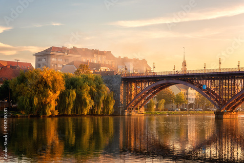 Amazing view of Maribor Old city, Main bridge (Stari most) on the banks of Drava river at sunrise, Slovenia. Scenic cityscape with blue sky, morning mist and reflection, outdoor travel background