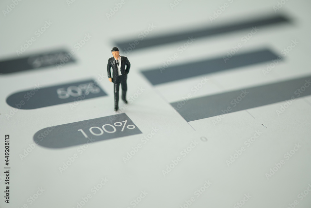 Miniature businessman standing on bar chart step from fifty percent to one hundred percent. Miniature businessman standing on bar chart step from fifty percent to one hundred percent.