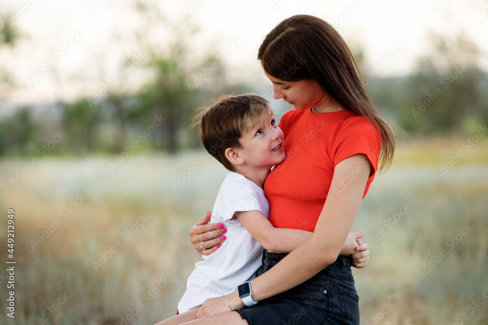 Candid authentic family portrait. Casual mom with her son in confidential conversation In Rural Settings. Young woman with child on countryside background Candid authentic family portrait. Casual mom with her son in confidential conversation In Rural Settings. Young woman with child on countryside background