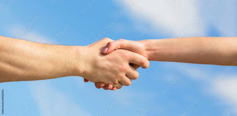 Giving a helping hand. Lending a helping hand. Solidarity, compassion, and charity, rescue. Hands of man and woman on blue sky background Giving a helping hand. Lending a helping hand. Solidarity, compassion, and charity, rescue. Hands of man and woman on blue sky background