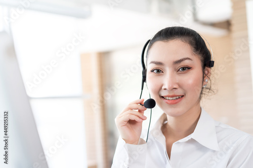 Smiling Asian call center woman. Female customer support operator with headset working in the office. Contact center and customer service by headphone concept