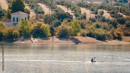 A person kayaking on an Andalusian lake with olive trees around