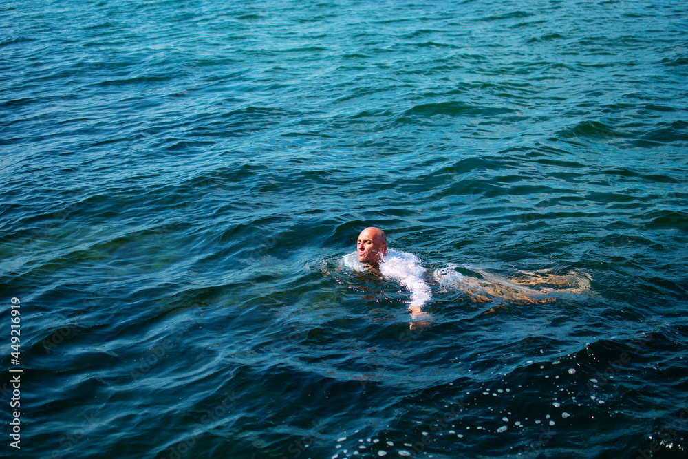 Man or businessman in white wet shirt swimming in the ocean or sea