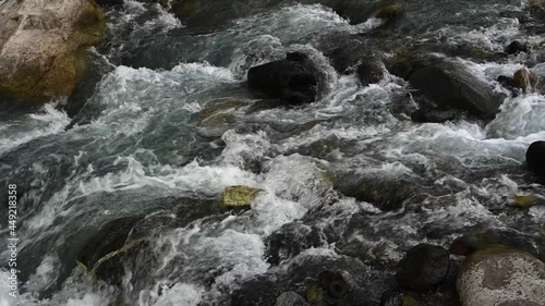 Slow motion of wild clear mountain river , stream flowing through rocks. Close up of river stones with flowing water, clean water flowing in a mountain river