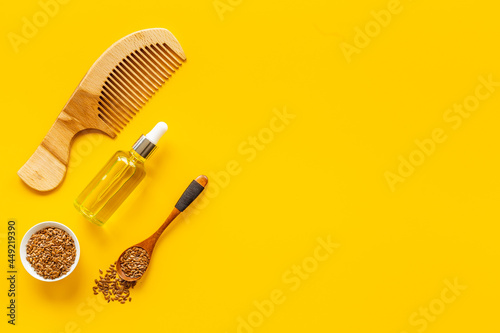 Hair treatment oil with seeds and wooden hair comb. Top view