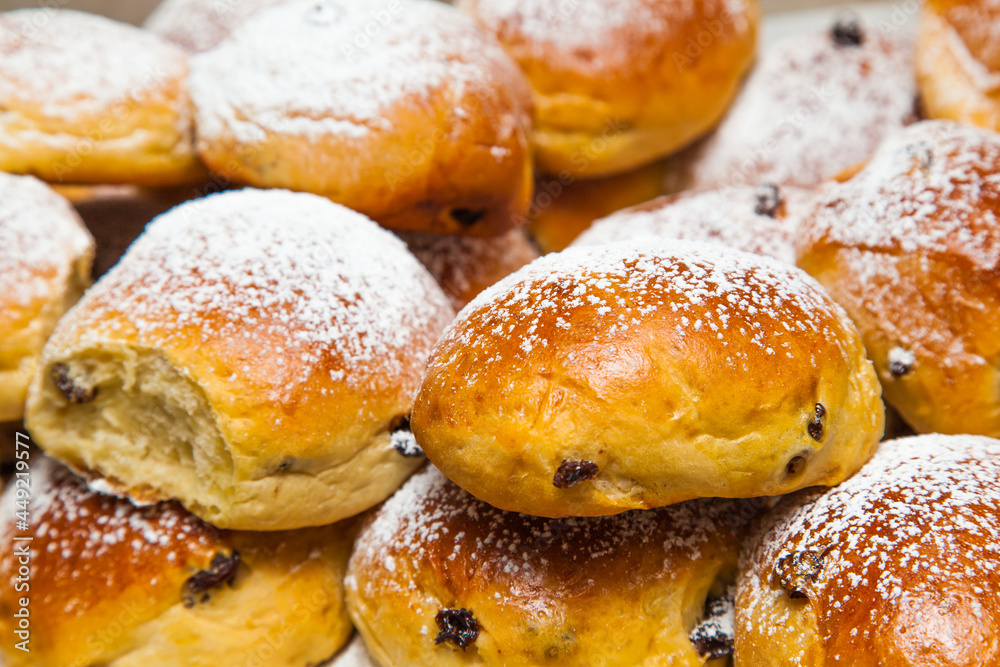 Bakery products. Buns with raisins covered with powdered sugar, close-up.