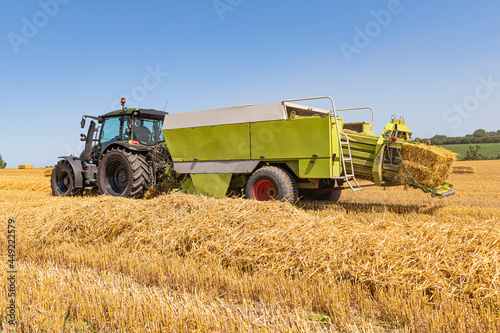 Tractor with straw baler on the harvested grain field 5620