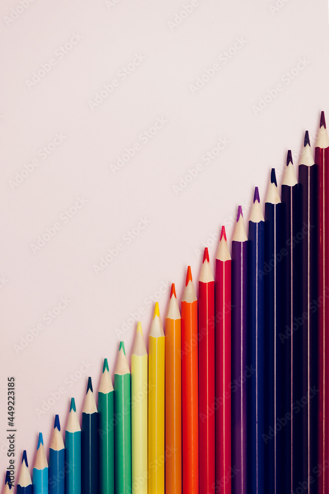 Colored pointed pencils lie on a pink background with space for copying. School supplies or school preparation. Top view. Colored pointed pencils lie on a pink background with space for copying. School supplies or school preparation. Top view.