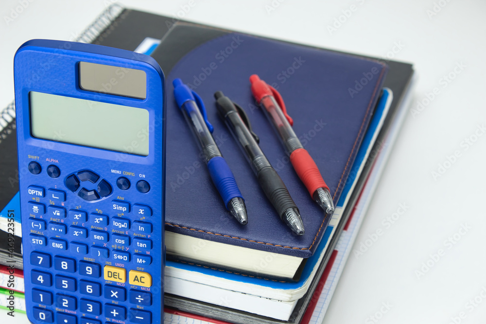 close-up of school tool set with notebooks, diaries, calculator, and colored pens ready for back to school on white background close-up of school tool set with notebooks, diaries, calculator, and colored pens ready for back to school on white background