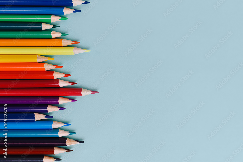 Colored sharpened pencils lie on a blue background with space for copying. School supplies or school preparation. Top view. Colored sharpened pencils lie on a blue background with space for copying. School supplies or school preparation. Top view.