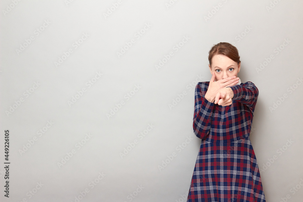 Portrait of girl pointing with finger at you, covering mouth with hand Portrait of girl pointing with finger at you, covering mouth with hand