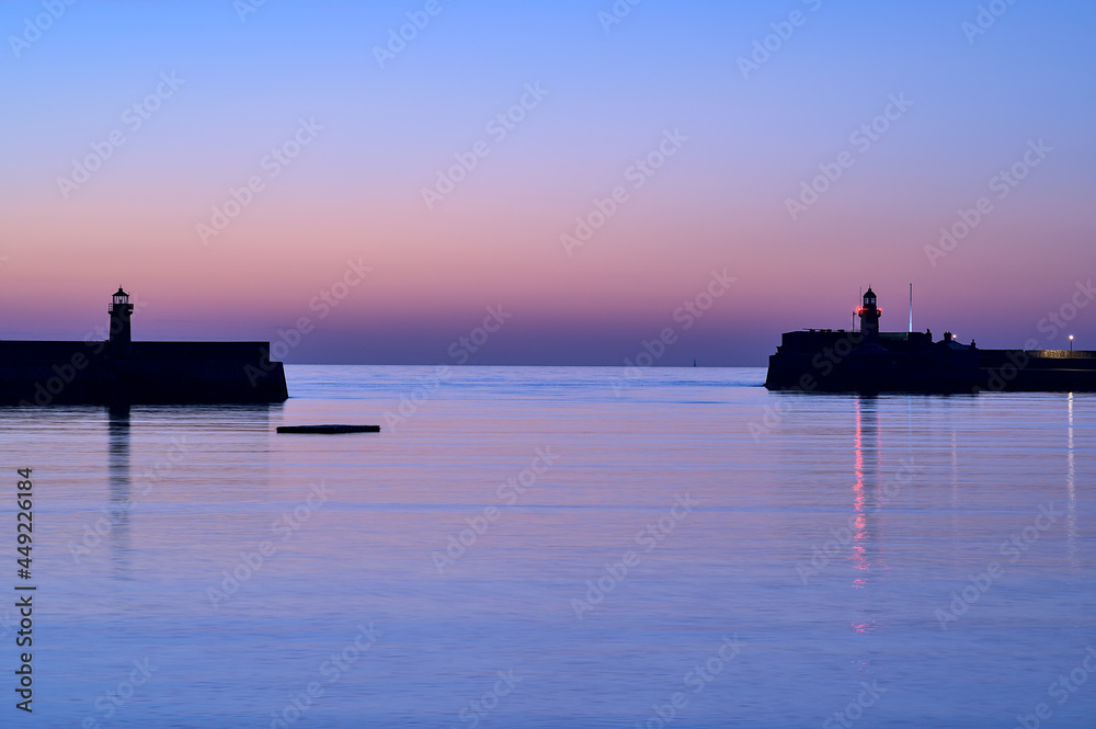 Spectacular early morning view of West and East Pier lighthouses of famous Dun Laoghaire harbor during the blue hour before sunrise, Dublin, Ireland. Marine themed. Purple morning colors