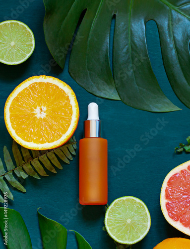 Fotografia Cosmetic flat lay with vitamin C serum and citrus on the back wooden background