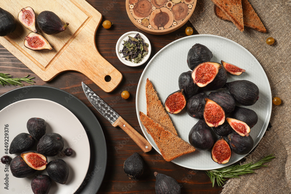 Delicious ripe figs, spice and bread served on dark wooden board, flat lay. Tasty figs freshly cut in half. Healthy food concept. Top view.