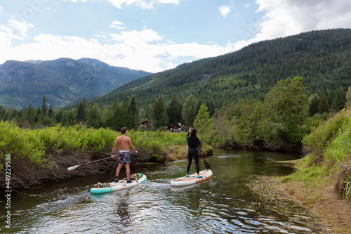 Adventurous Hispanic Athletic Man and Caucasian Woman paddle boarding on The River of Golden Dreams. Located in Whistler  BC  Canada.