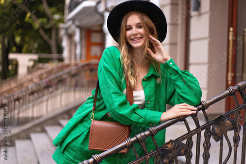 Outdoor portrait of elegant pretty woman posing on the street at European city, stylish outfit hat and accessorizes . photo