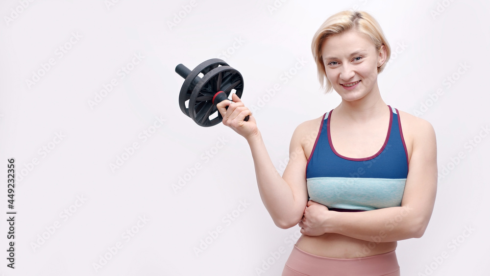 Girl holding an ab wheel roller dressed in activewear. Sporty girl posing for the camera. Concept of fitness and gym. Isolated over white background studio. Healthy lifestyle and good body condition. Girl holding an ab wheel roller dressed in activewear. Sporty girl posing for the camera. Concept of fitness and gym. Isolated over white background studio. Healthy lifestyle and good body condition.