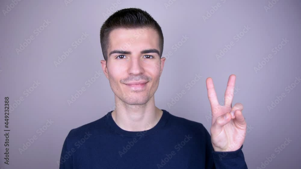 Smiling man shows with fingers the sign of victory Smiling man shows with fingers the sign of victory