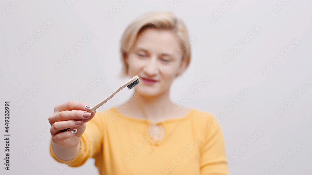 Cute girl holding a toothbrush. Morning routine. The girl is dressed in a yellow top smiling and posing for the camera. Dental care. Personal hygiene concept. Isolated shot. Cute girl holding a toothbrush. Morning routine. The girl is dressed in a yellow top smiling and posing for the camera. Dental care. Personal hygiene concept. Isolated shot.