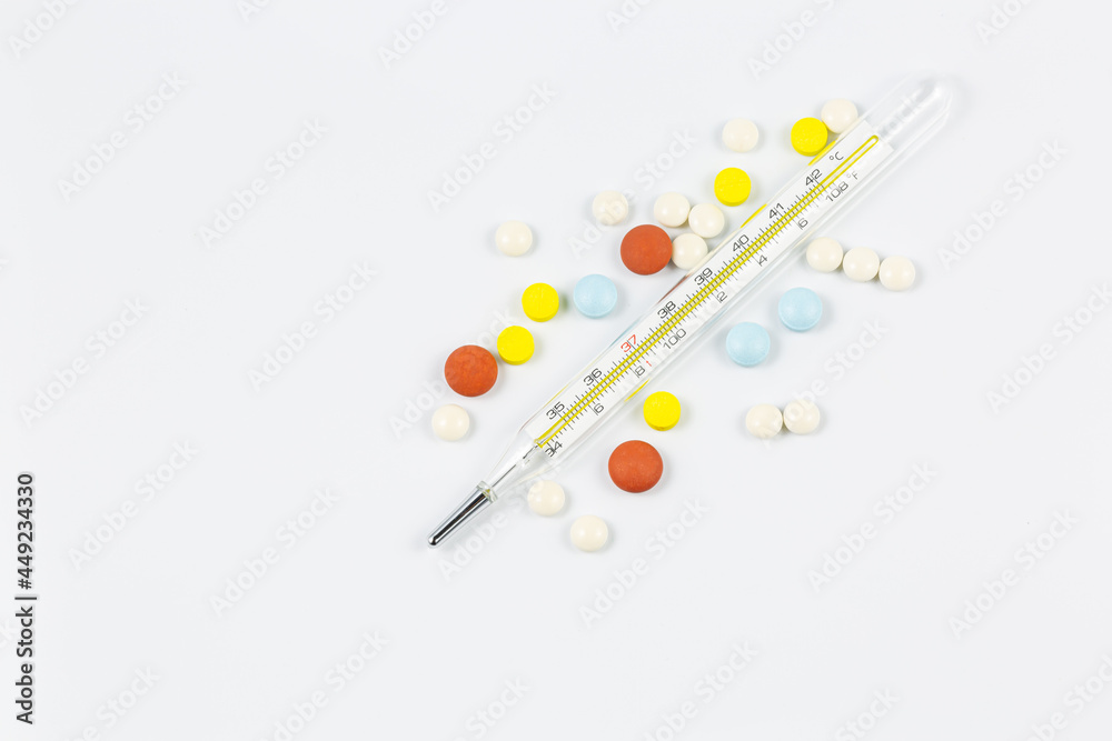 Medical device thermometer, with pills in the shape of a heart, isolated on a white background with hard shadows. Heat. Medical device. Medicine concept. Copy space