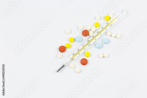Medical device thermometer  with pills in the shape of a heart  isolated on a white background with hard shadows. Heat. Medical device. Medicine concept. Copy space