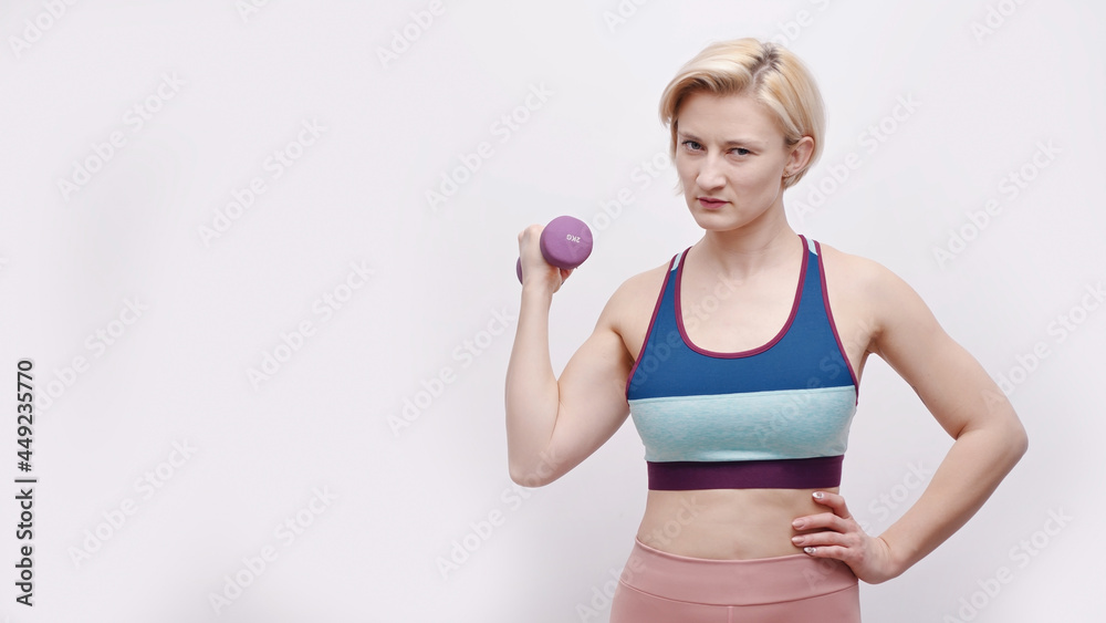 Strong girl holding a dumbbell and dressed in activewear. Sporty girl posing for the camera. Concept of losing weight. Isolated over white background. Healthy lifestyle and good body condition. Strong girl holding a dumbbell and dressed in activewear. Sporty girl posing for the camera. Concept of losing weight. Isolated over white background. Healthy lifestyle and good body condition.