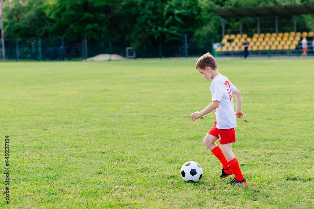 8 years old boy child playing football on playing field. Child playing football.