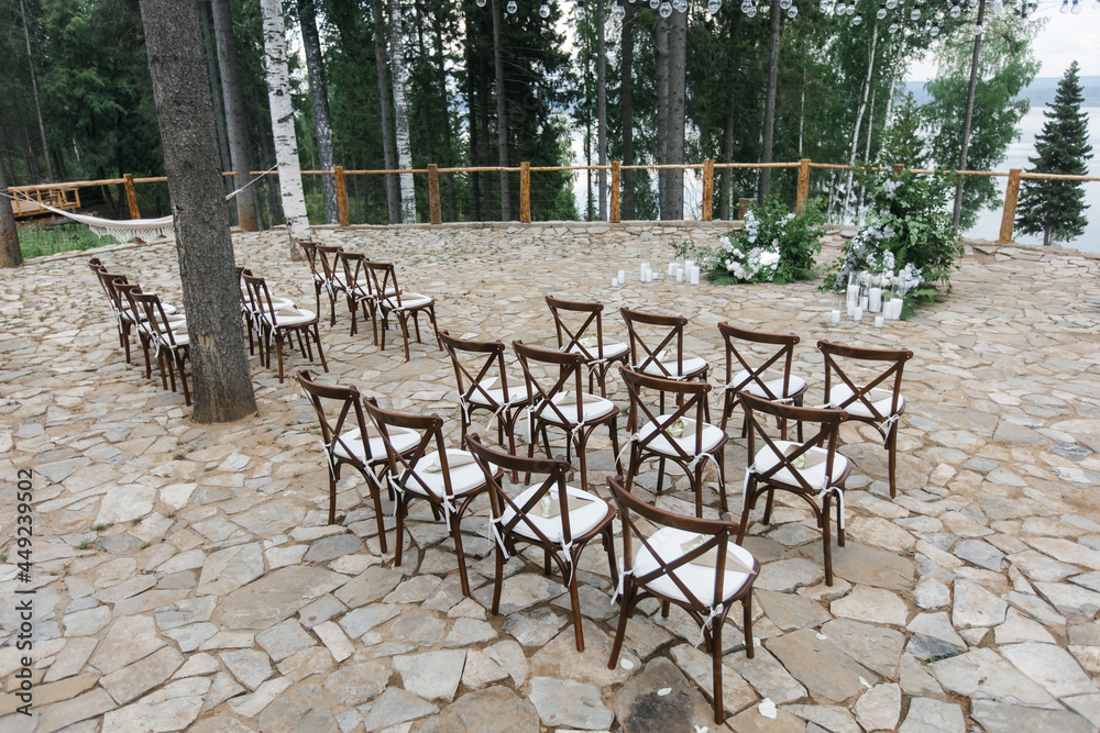 brown wooden chairs with cross-backs. Wedding decoration in nature, against the backdrop of the river and pine trees. natural wedding decor in a rustic style. holiday concept.