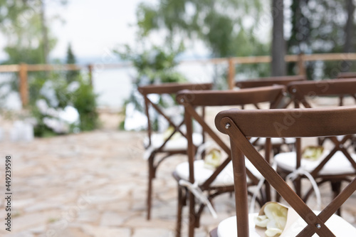 brown wooden chairs with crisscross back. White pillows on chairs and envelopes with white rose petals. against the backdrop of nature on a stone floor. holiday concept.