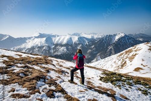  Winter hiking scene. Woman tourist in the mountains with a backpack. Active rest in one with nature. 