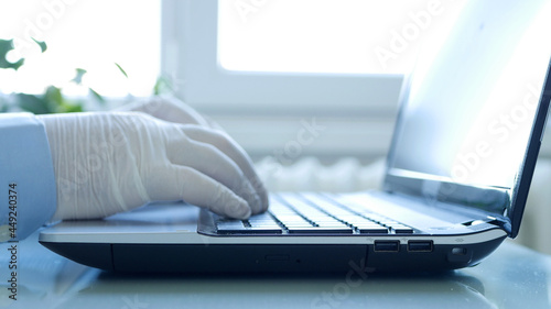 Closeup Image with Hands Wearing Protective Gloves Using the Laptop Keypad