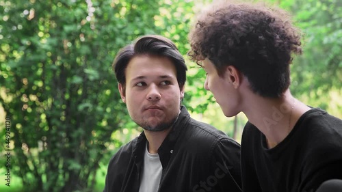A guy feeds grapes to another guy in the park in the summer