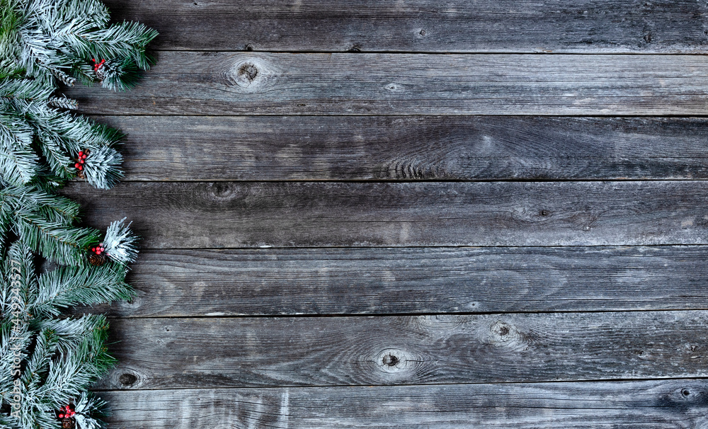 Frosted snow covered evergreen branches plus red berries on weathered wooden planks for a merry Christmas or happy New Year holiday celebration concept Frosted snow covered evergreen branches plus red berries on weathered wooden planks for a merry Christmas or happy New Year holiday celebration concept