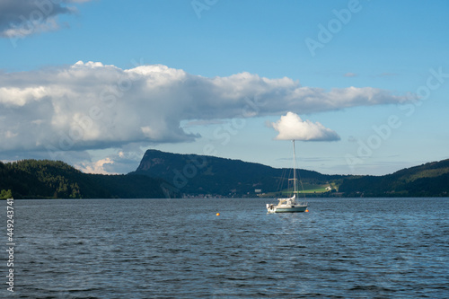 A sailing boat lying on the water of Lac de Joux, Switzerland, in afternoon sunlight
