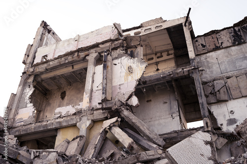 A ruined large gray building with a pile of concrete slabs and beams. Background.