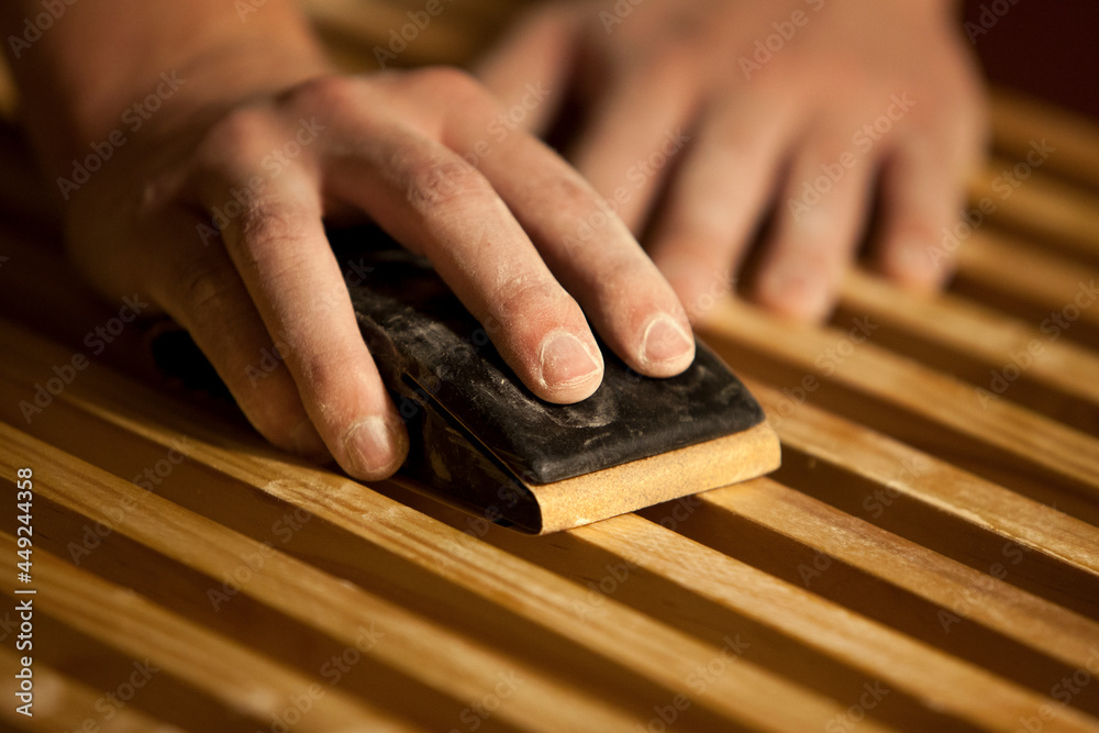 Carpenter's hands sanding a woodworking project.