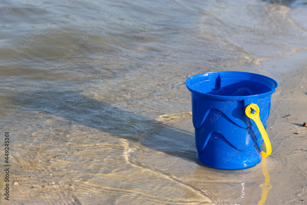 blue children's bucket with grains of sand on the beach blue children's bucket with grains of sand on the beach
