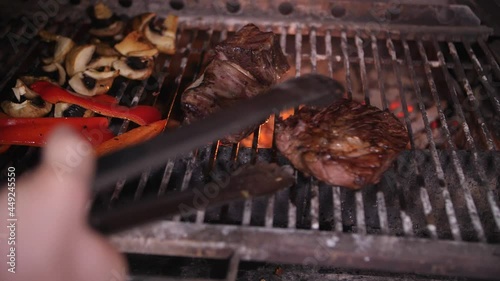 meat and vegetables are grilled and turned over with tongs photo