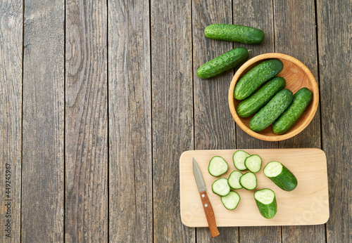 Whole and sliced ripe cucumbers on a cutting board, top view.